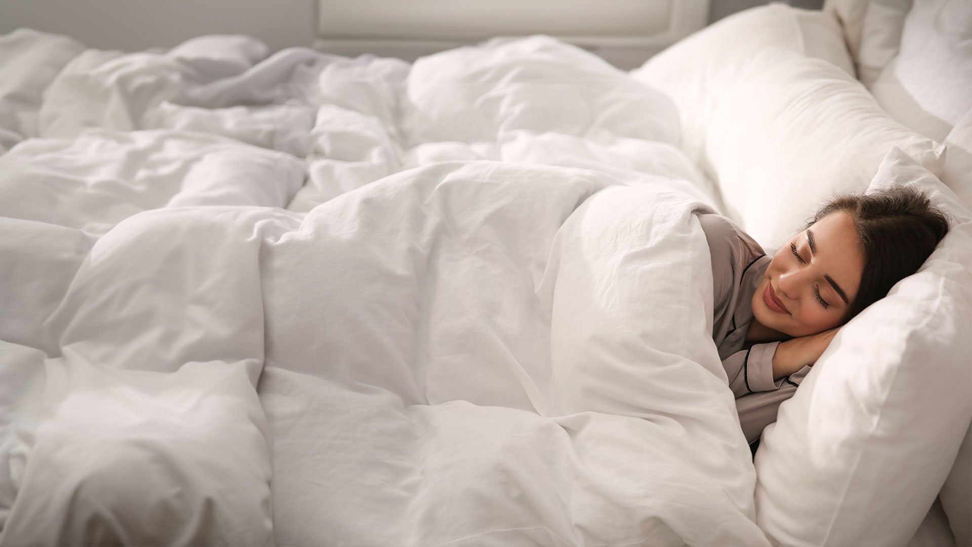 Dieses Bild zeigt eine junge Frau auf einem Bett, eingehüllt in kuscheligen casimum® Bettdecken.