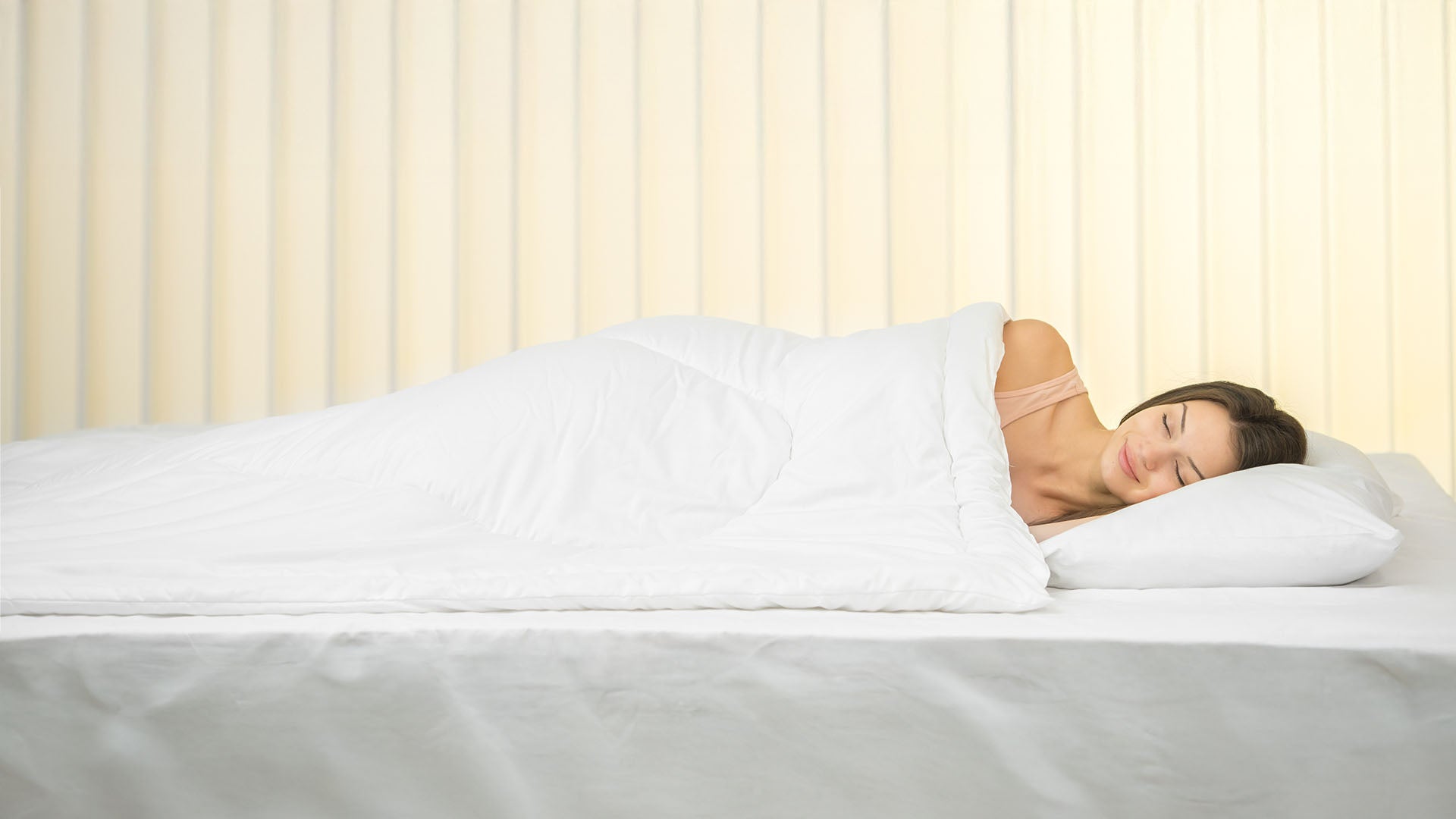 Dieses Bild veranschaulicht eine junge Frau im Bett auf einem Kopfkissen mit einer Polyester-Bettdecke.