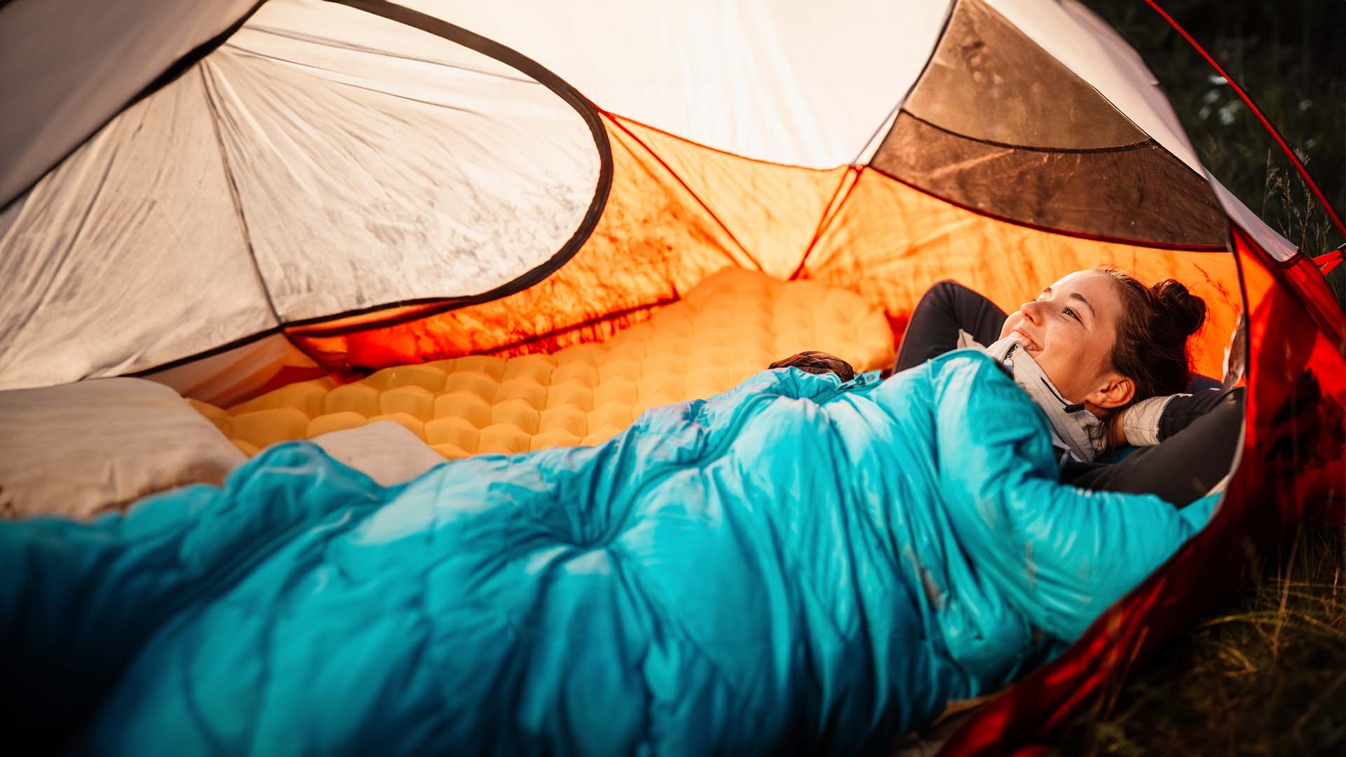 Dieses Foto veranschaulicht eine junge Frau in einem Zelt auf einem Reisekissen.